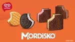 En un fondo naranja se aprecian los 5 mordiskos que tiene la marca (Pay de Limón, Mordisko Oreo, Mordisko Clásico, Mordisko Fresa, Mordisko Chocolate)